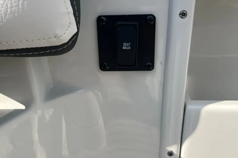 Slide: The Image of 2025 Crownline Eclipse E235 seat back control button on white interior panel. - 17