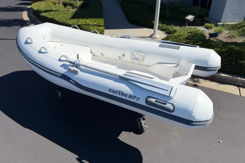 Slide: The Image of Inflatable Caribe MVP11 boat, 2025 model, displayed outdoors on pavement. - 11