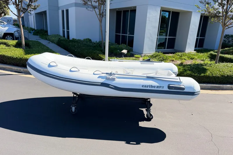 Slide: The Image of Inflatable Caribe MVP11 boat, 2025 model, displayed outdoors on a wheeled stand. - 12