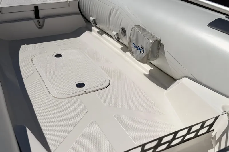 Slide: The Image of Interior of a 2025 Caribe MVP11 boat, featuring a clean, white seating area. - 20