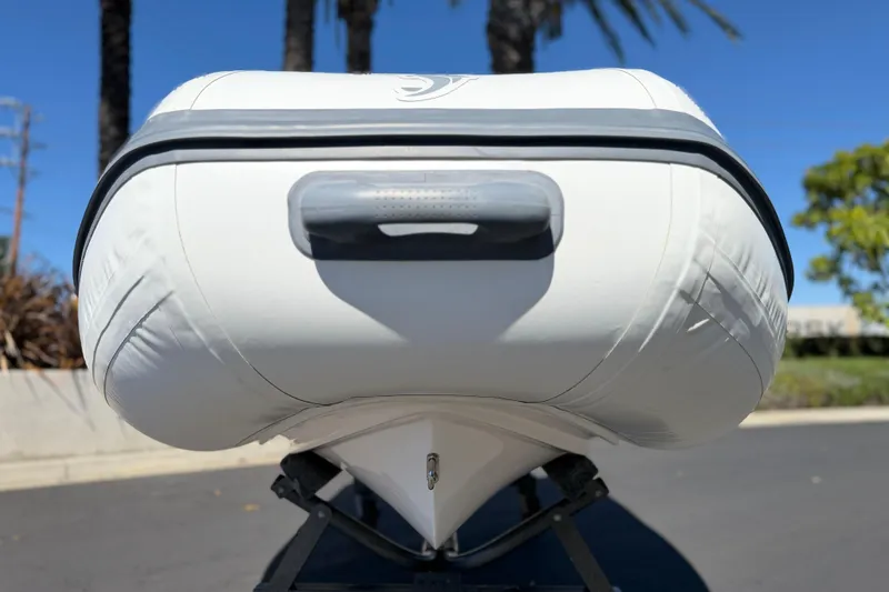 Slide: The Image of Front view of a 2025 Caribe MVP11 inflatable boat on a trailer, under clear blue sky. - 23