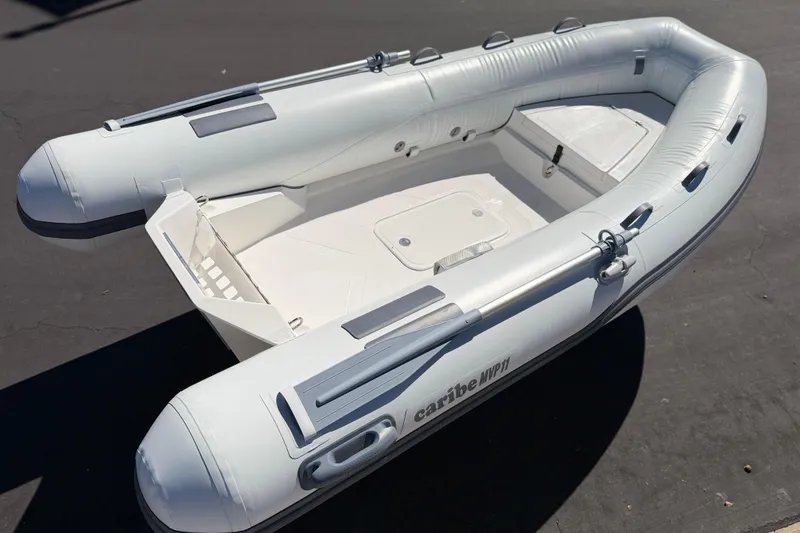 Slide: The Image of Inflatable boat Caribe MVP11, 2025 model, on pavement in sunlight. - 24