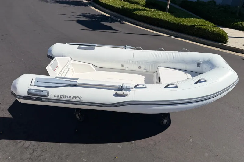 Slide: The Image of 2025 Caribe MVP11 inflatable boat on pavement, showcasing sleek design and modern features. - 25