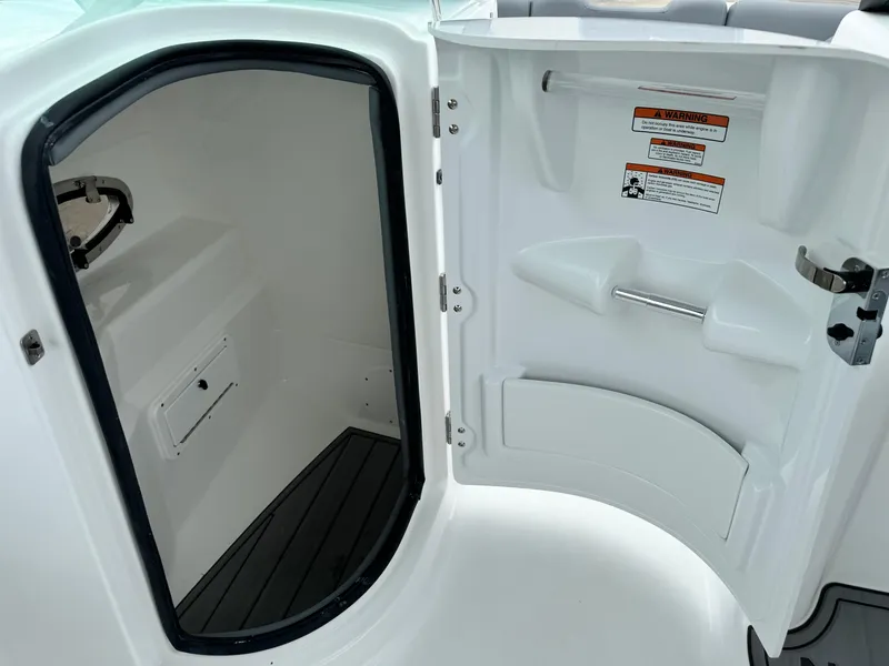 Slide: The Image of 2025 NauticStar 243 DC Deck boat interior storage compartment with open door. - 24