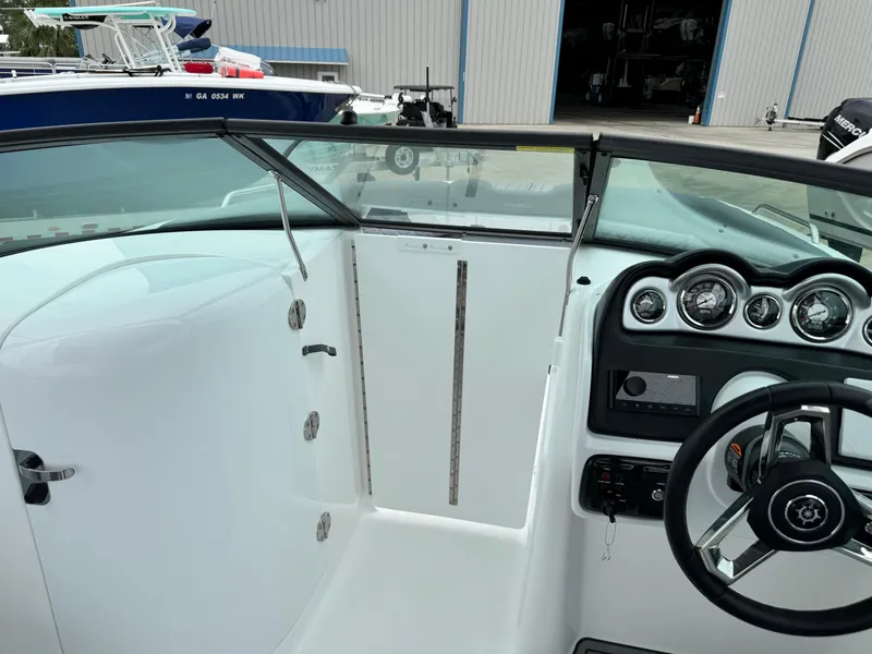 Slide: The Image of 2025 NauticStar 243 DC Deck boat interior with steering wheel and dashboard controls. - 26