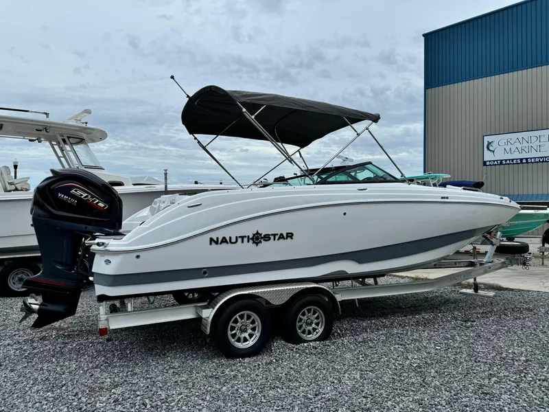 Slide: The Image of 2025 NauticStar 243 DC Deck boat on trailer, parked at marina. - 6