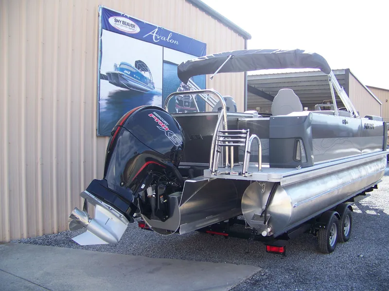 Slide: The Image of 2025 Avalon GeoFish23RF pontoon boat with powerful outboard motor, displayed outdoors. - 2