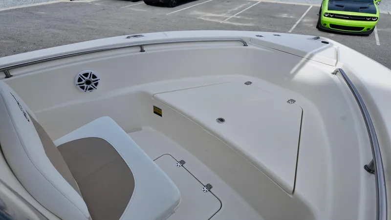 Slide: The Image of 2025 Bulls Bay 200CC boat interior with seating and storage, parked near a green car. - 9