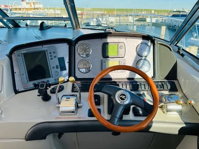Slide: The Image of 2004 Sea Ray 390 Sundancer helm with wood steering wheel and navigation instruments. - 7