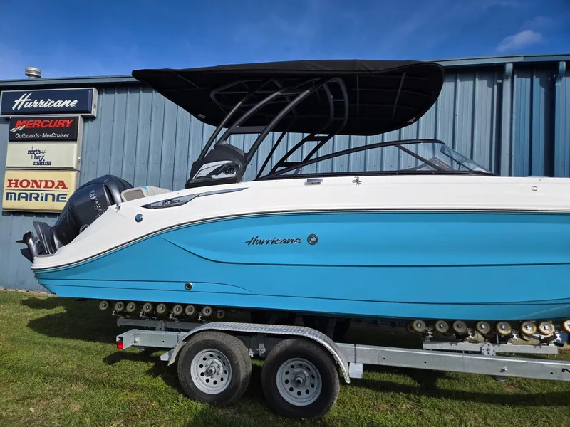 Slide: The Image of 2025 Hurricane SunDeck 2600 OB boat on trailer, blue hull, black canopy. - 2