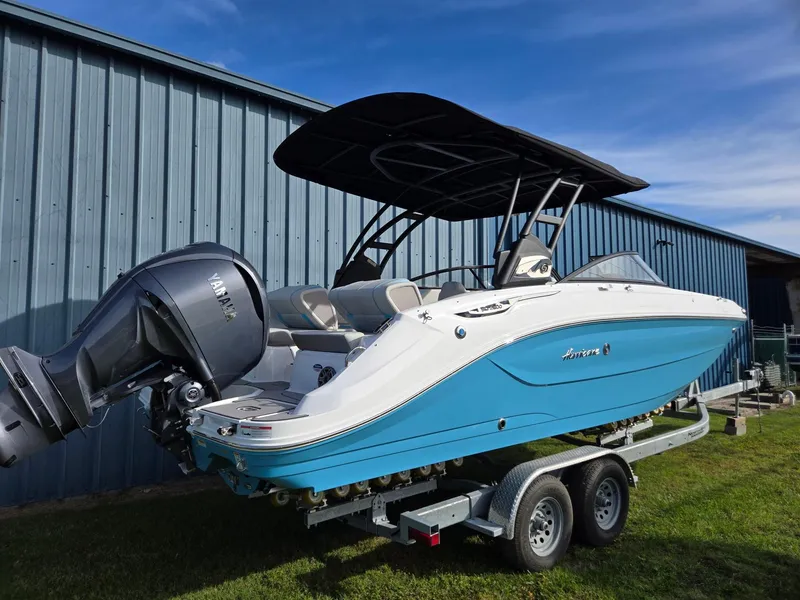 Slide: The Image of 2025 Hurricane SunDeck 2600 OB boat on trailer, blue and white design, parked outdoors. - 3