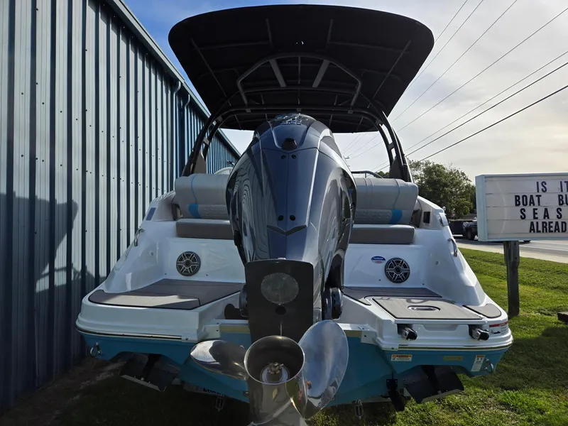 Slide: The Image of 2025 Hurricane SunDeck 2600 OB boat with outboard motor, docked near a metal building. - 4