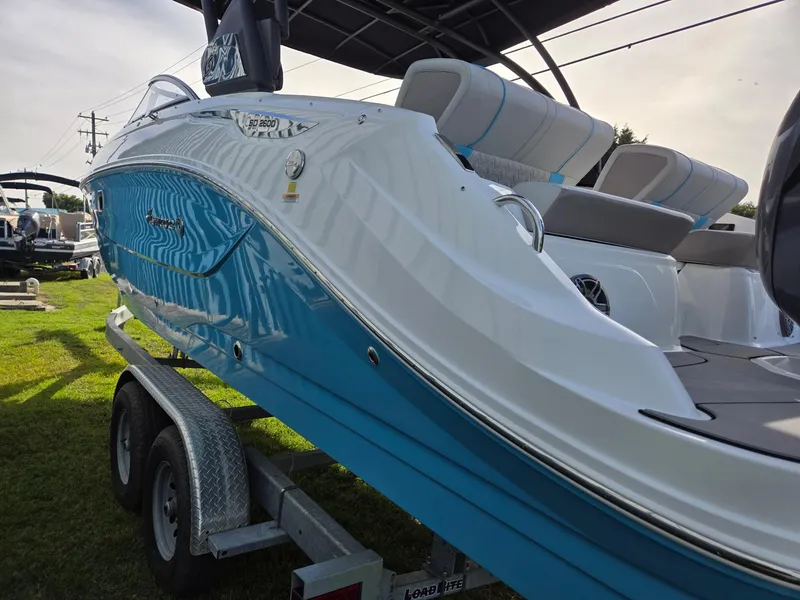 Slide: The Image of 2025 Hurricane SunDeck 2600 OB boat on trailer, blue and white exterior, parked on grass. - 5