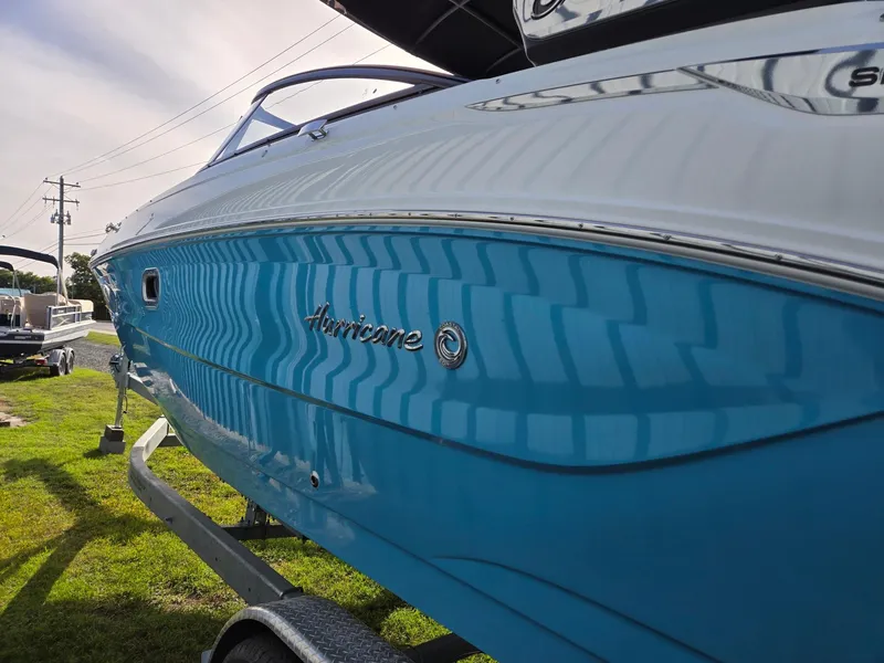 Slide: The Image of 2025 Hurricane SunDeck 2600 OB boat, blue hull, parked on trailer, side view. - 6