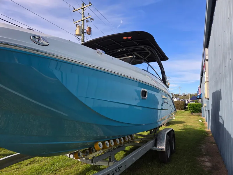 Slide: The Image of 2025 Hurricane SunDeck 2600 OB boat on trailer, blue hull, parked outdoors. - 7