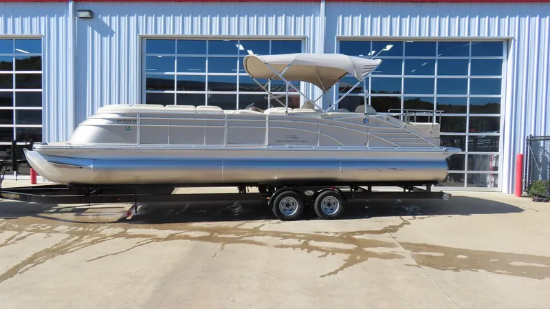 Slide: The Image of 2013 Bennington 2875 QCW I/O pontoon boat on trailer, parked outside a garage. - 2