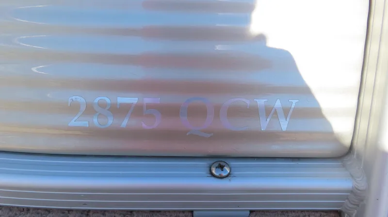 Slide: The Image of 2013 Bennington 2875 QCW I/O model nameplate on metallic surface. - 9
