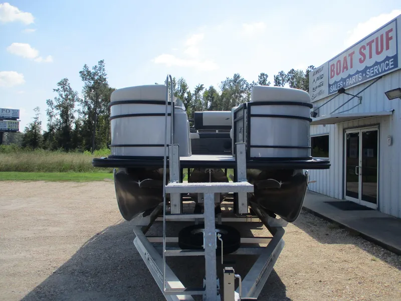 Slide: The Image of 2025 Starcraft EXS-3DL pontoon boat on trailer near boat service shop. - 6