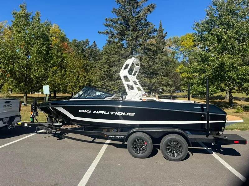 Slide: The Image of 2025 Nautique Ski 200 Open Bow boat on trailer in a park setting. - 1