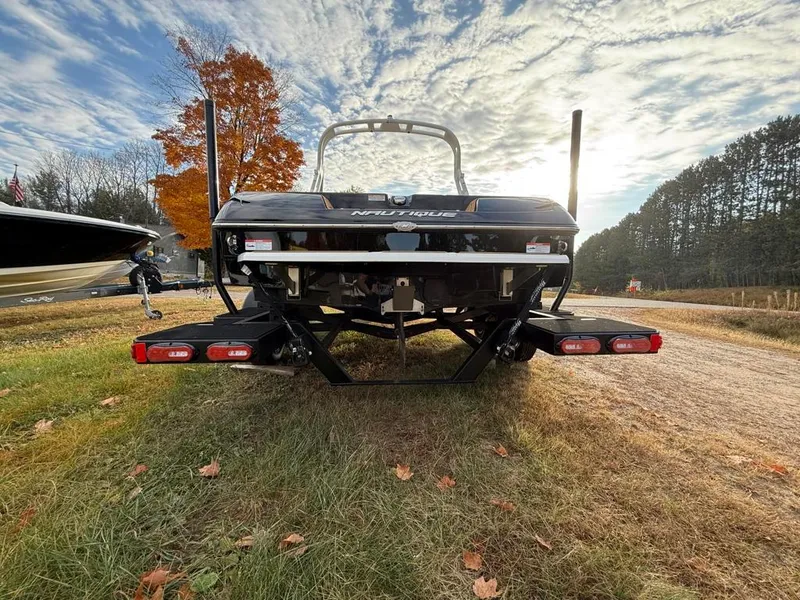 Slide: The Image of 2025 Nautique Ski 200 Open Bow boat on grassy landscape under cloudy sky. - 12