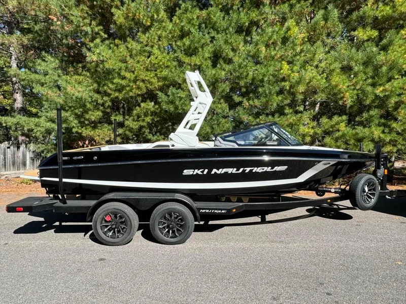 Slide: The Image of 2025 Nautique Ski 200 Open Bow boat on trailer, parked outdoors. - 3