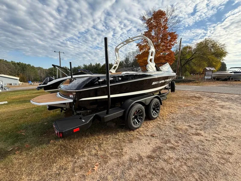Slide: The Image of 2025 Nautique Ski 200 Open Bow boat on trailer, parked outdoors. - 4