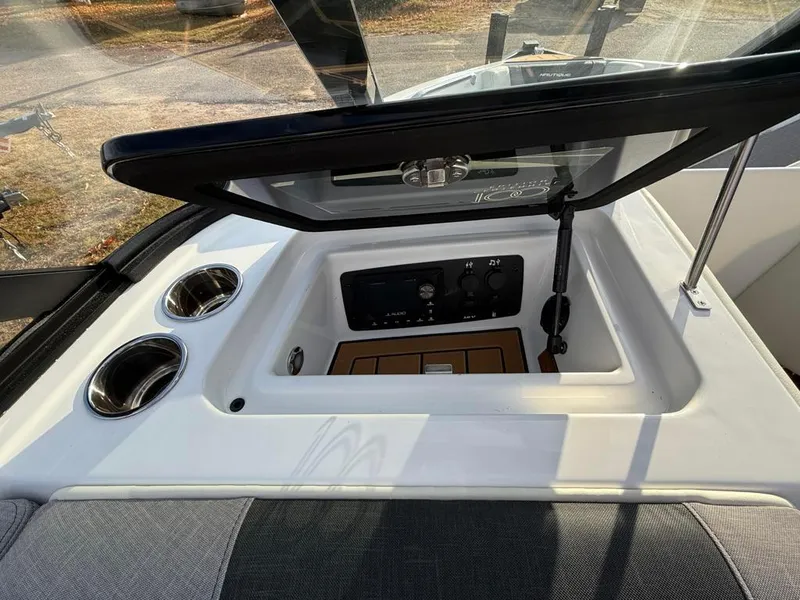 Slide: The Image of 2025 Nautique Ski 200 Open Bow dashboard with cup holders and control panel. - 47