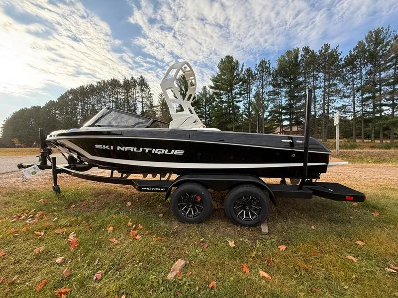 Slide: The Image of 2025 Nautique Ski 200 Open Bow boat on trailer, parked outdoors. - 8