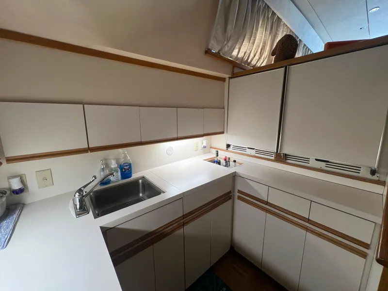 Slide: The Image of 1989 Bertram 50 Convertible yacht kitchen with white cabinets and sink. - 23