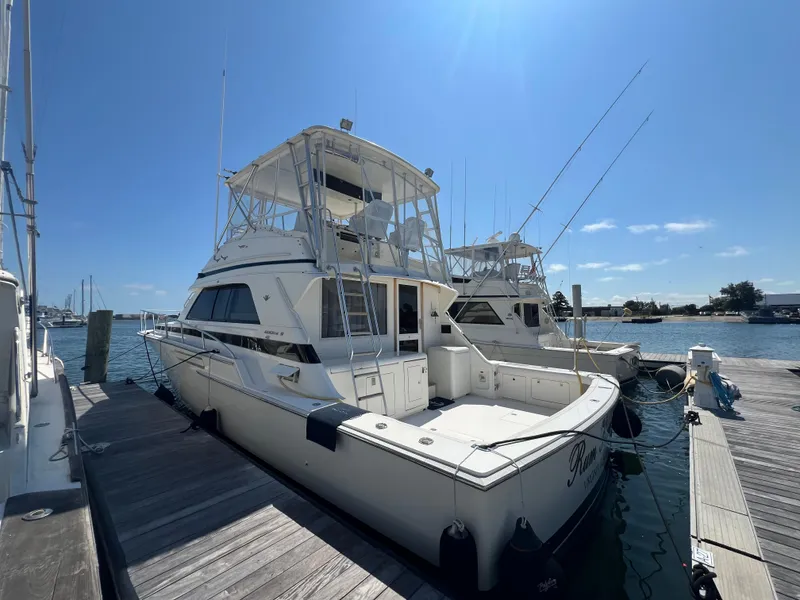 Slide: The Image of 1989 Bertram 50 Convertible yacht docked at marina under clear blue sky. - 3