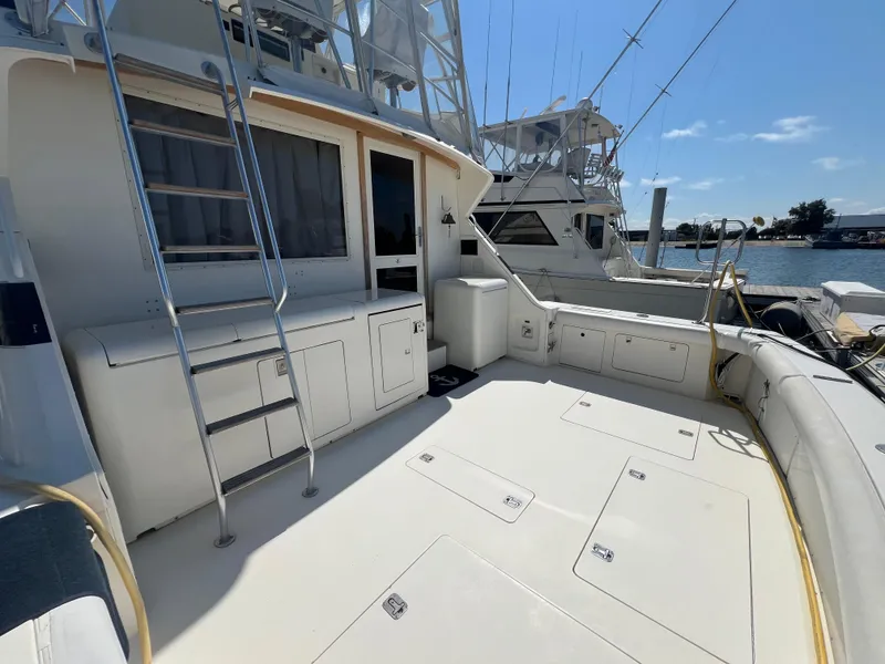 Slide: The Image of 1989 Bertram 50 Convertible yacht deck with ladder and storage, docked by the water. - 6