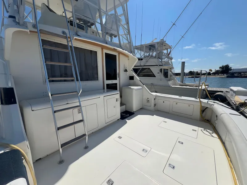 Slide: The Image of 1989 Bertram 50 Convertible yacht deck with ladder and storage, docked by the water. - 7