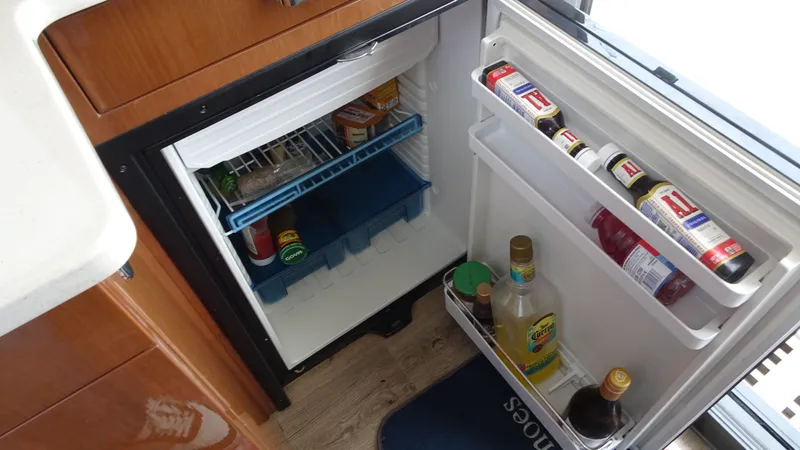 Slide: The Image of Mini fridge inside 2018 Carver C34 Coupe, stocked with beverages and condiments. - 28