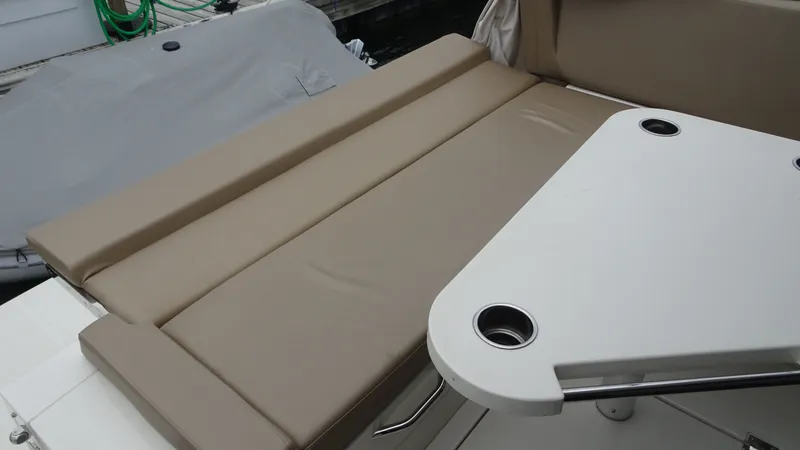 Slide: The Image of 2018 Carver C34 Coupe boat interior with beige seating and white table. - 14