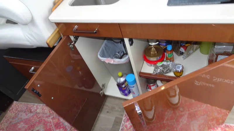 Slide: The Image of Interior of 2018 Carver C34 Coupe showing open kitchen cabinets with various items. - 29