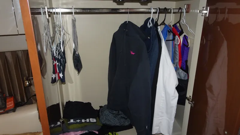 Slide: The Image of Closet inside 2018 Carver C34 Coupe with hanging clothes and folded garments. - 34