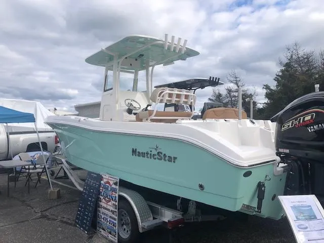 Slide: The Image of 2023 NauticStar 242L Offshore boat displayed on a trailer under cloudy skies. - 2