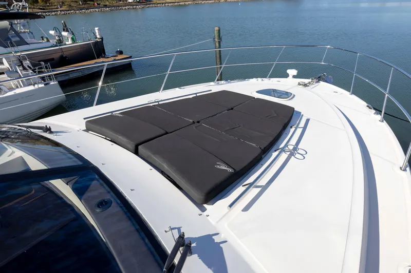 Slide: The Image of 2016 Sea Ray 510 Sundancer yacht with sun pads on deck, docked by calm waters. - 28
