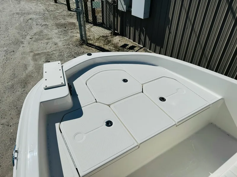 Slide: The Image of 2025 Bayliner Trophy T18 boat deck with storage compartments, docked near a wooden fence. - 16