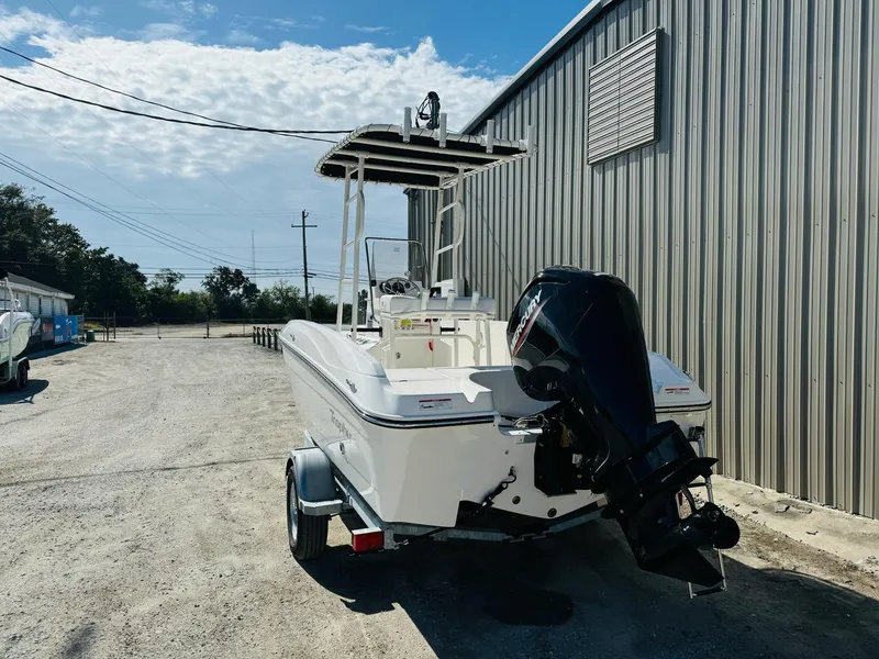 Slide: The Image of 2025 Bayliner Trophy T18 boat on trailer, parked beside a metal building under a clear sky. - 6