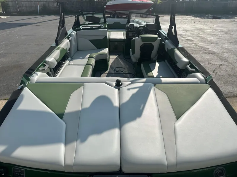 Slide: The Image of 2022 Axis A22 boat interior with green and white seating, parked outdoors. - 11