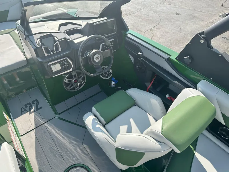 Slide: The Image of 2022 Axis A22 boat interior with green and white seating, modern dashboard, and steering wheel. - 13