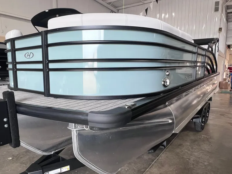 Slide: The Image of 2024 Harris Sunliner 230 pontoon boat in showroom, showcasing sleek design and modern features. - 2
