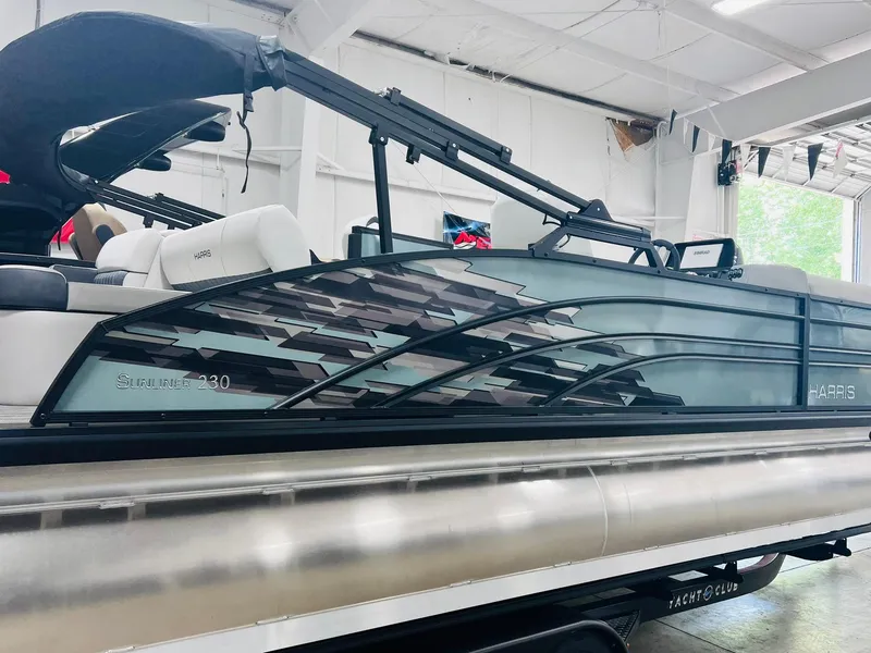 Slide: The Image of 2024 Harris Sunliner 230 pontoon boat in a showroom setting. - 4