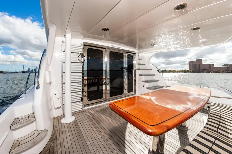 Slide: The Image of 2007 Hatteras 64 Motor Yacht deck with wooden table and waterfront view. - 20