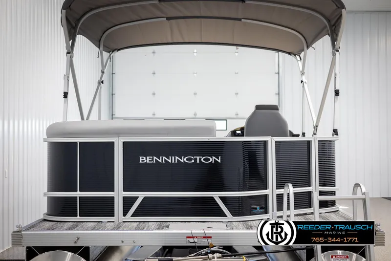 Slide: The Image of 2025 Bennington 21 SLSE pontoon boat in showroom, featuring sleek design and canopy. - 7