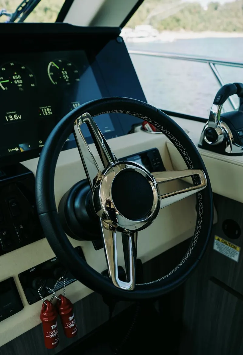 Slide: The Image of Steering wheel of a 2021 Regal 38 Grande Coupe yacht, featuring modern dashboard controls. - 12