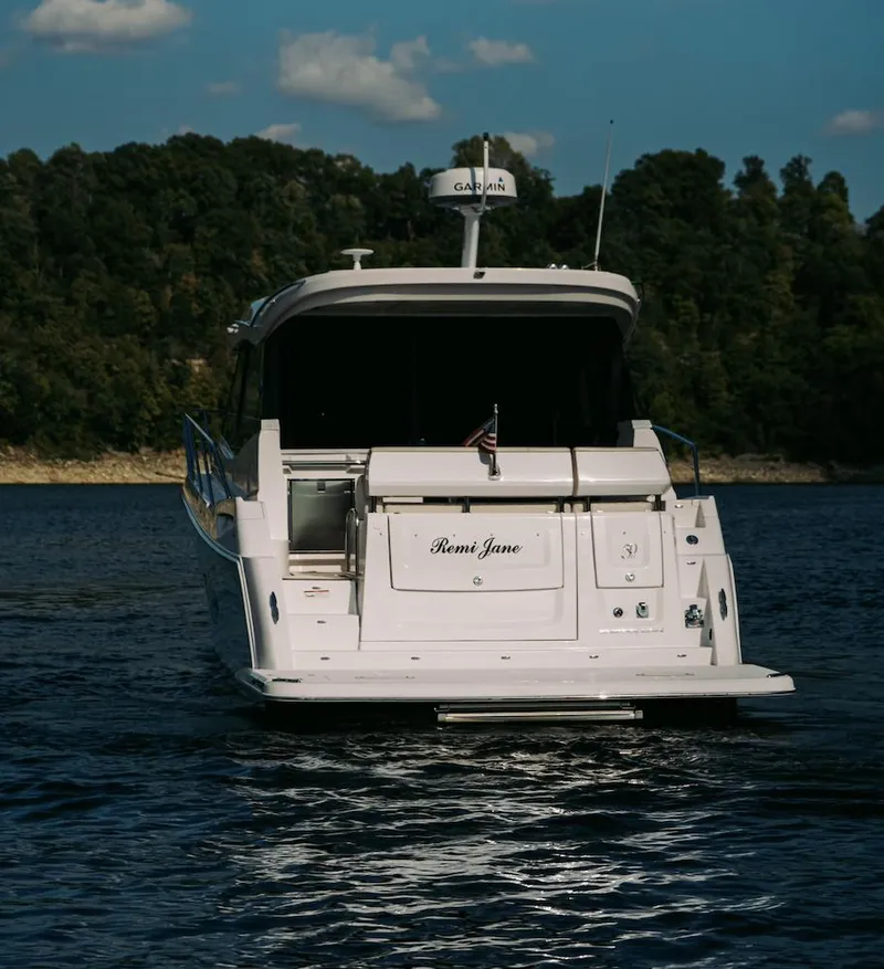 Slide: The Image of 2021 Regal 38 Grande Coupe yacht on a serene lake with forested background. - 24