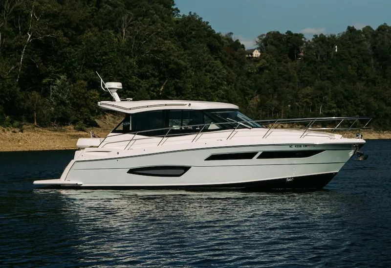 Slide: The Image of 2021 Regal 38 Grande Coupe yacht on a serene lake with forested background. - 3