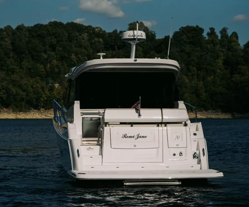 Slide: The Image of 2021 Regal 38 Grande Coupe yacht on a serene lake with forested background. - 5